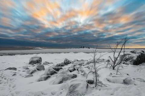 A tranquil cloudscape of dramatic evening sky and snow covered half frozen la Stock Photos