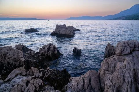 A tranquil coastal scene at sunset featuring rugged stone formations domina.. Stock Photos