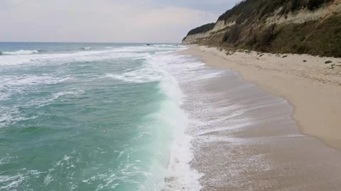 A tranquil coastal scene with turquoise waves gently washing onto a sandy beach Stock Footage 285640848