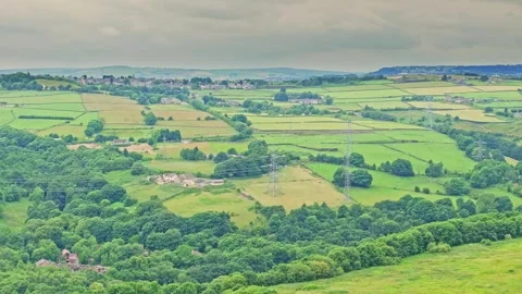 A tranquil countryside landscape with a patchwork of green fields bordered 스톡 동영상 285769526