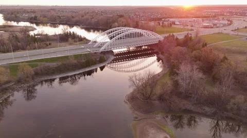 Tranquil dawn setting with an arched bridge spanning over a peaceful river Stock Footage 274136141