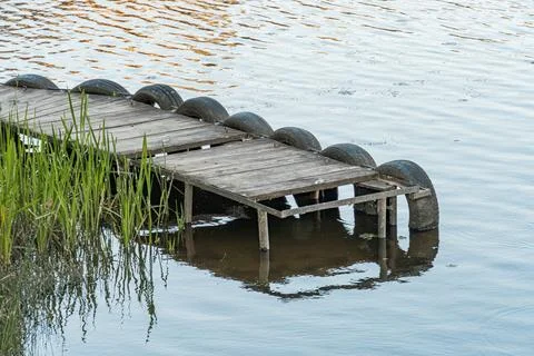 A tranquil, elevated view of a floating wooden dock in water possibly lake or Stock Photos