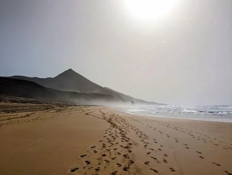 Tranquil Empty Beach with Mountain and Footprints in the Sand at Sunset, Co.. Foto stock