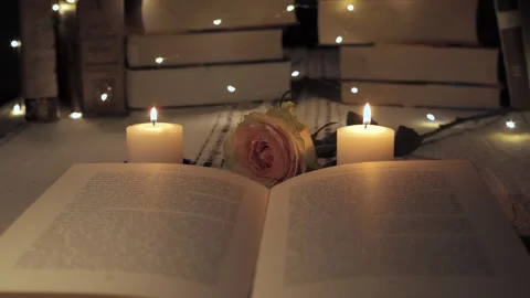 A tranquil evening with candles, an open book, and a rose among glowing lights Stock Footage 292608572