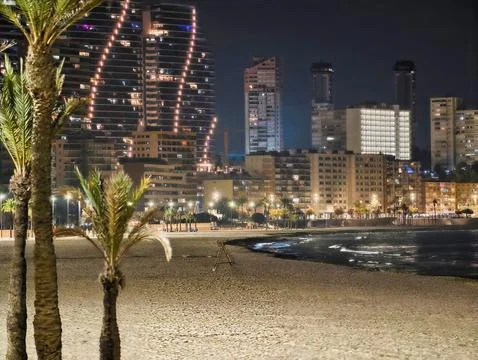 Tranquil Evening Seashore Featuring Shimmering Highrise Reflections And Softly Stock Photos