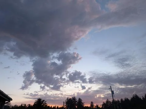 A tranquil evening sky featuring layered dark storm clouds Stock Photos