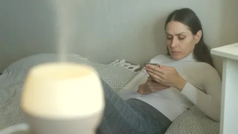 Tranquil female practicing relaxation with device by steamfilled diffuser in Stock Footage 322165357