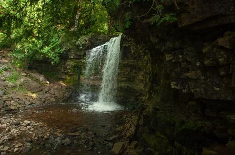 Tranquil Forest Waterfall Cascading Over Mossy Rock Cliff Foto stock