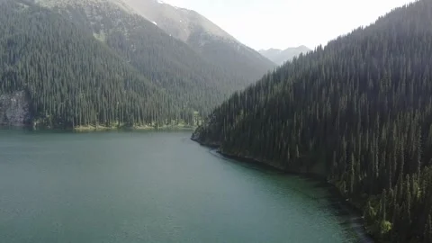 Tranquil glacial lake surrounded by dense forest at Kolsay Lakes, Kazakhstan Stock Footage 345410347