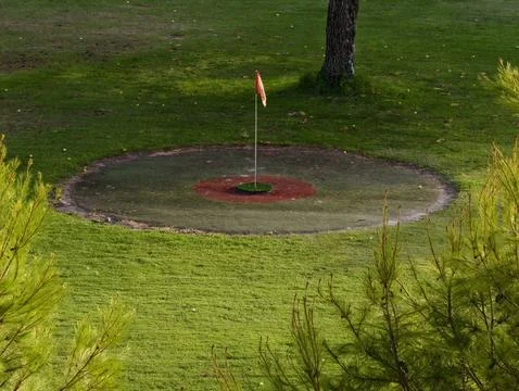 A tranquil golf course featuring a beautifully maintained green with a flag.. Stock Photos