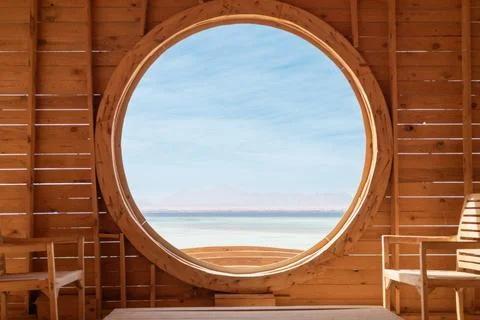 Tranquil indoor space with large circular window overlooking serene sea and Stock Photos