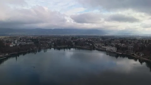 A tranquil Lake Bled sits below mountains and forests under a cloudy sky. Stock Footage 336467656