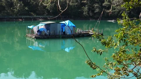 Tranquil Lake with Floating House Surrounded by Lush Foliage Stock Footage 268909701