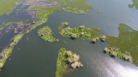 Tranquil Lake Scene with a Canoe Navigating Through Small Islands Under Sunny Stock Footage 316188130