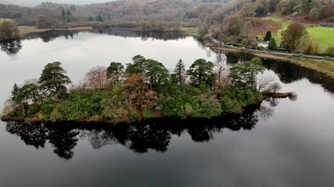 A tranquil lake scene features a tree-covered island with reflections. Stock Footage 293154678