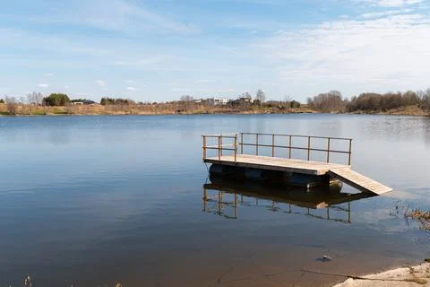 Tranquil lake scene showcasing a rustic wooden floating pier extending into.. Fotos Stock