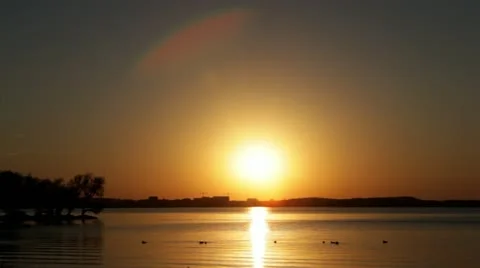 Tranquil lake at sunset, glowing orange, ducks Stock Footage 12371850