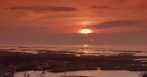 Tranquil lake surrounded by traffic and bushes under a cloudy sky during sunset Stock Footage 252871711