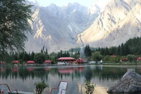 Tranquil Lakeside with Red-Roofed Cabins and Mountain Backdrop Stock Photos