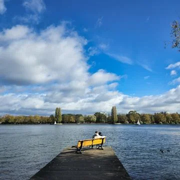 A Tranquil Lakeside Scene Featuring Couples Relaxing Together on a Cozy Wooden Stock Photos