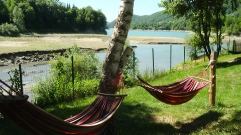 A tranquil lakeside scene with hammocks swaying in trees Stock Footage 313987045