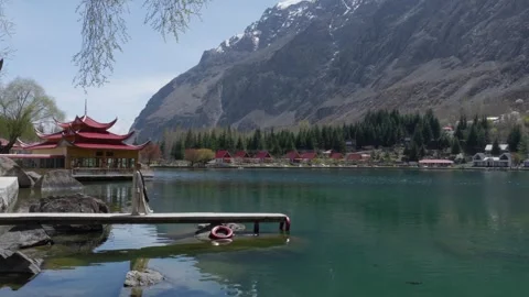 A tranquil lakeside scene in Pakistan, featuring a traditional Chinese-style Stock Footage 314456221