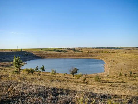 Tranquil landscape with barren ground, sparse vegetation, still lake, gentl.. Stock Photos