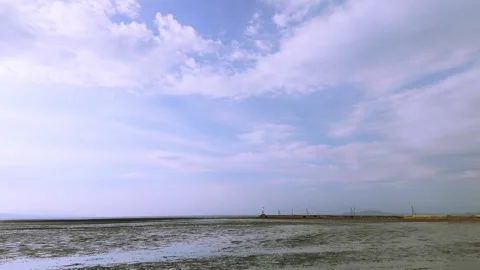 Tranquil Low Tide Beach Under a Vast Blue Sky in 4K Stock Footage 336391056