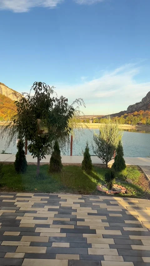 Tranquil mountain lake with cozy seating area surrounded by lush greenery Stock Footage 304879318