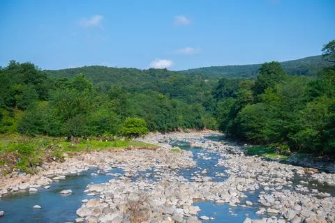 Tranquil Mountain River Streaming Through Verdant Valley Landscape Stock Photos