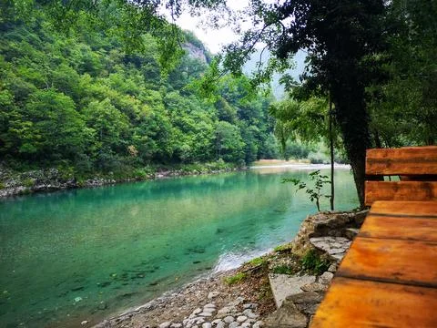 Tranquil Mountain Stream of Tara river by Rustic Wooden Bench Foto stock