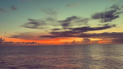 Tranquil ocean at sunset with colorful sky and scattered clouds creating a .. Stock Footage 338281748
