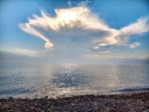 Tranquil ocean view with dramatic cloud formation at sunset Stock Photos