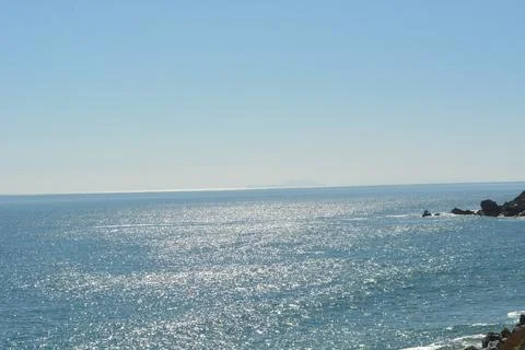 Tranquil Ocean View Reflecting Sunlight on a Calm Day by the Shore Stock Photos