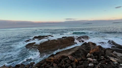 The Tranquil Ocean Waves Gently Crash Against the Rocky Shoreline at a Beautiful Stock Footage 303734831