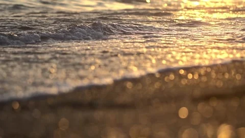 Tranquil ocean waves lapping gently onto sandy sea shore, slow motion, sunset Stock Footage 335763914