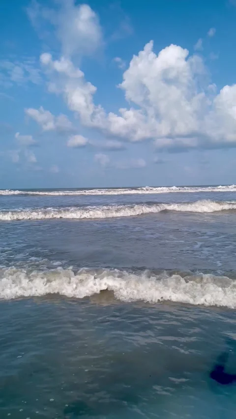 Tranquil ocean waves roll over a dark volcanic beach with foamy surf. Stock Footage 334163256