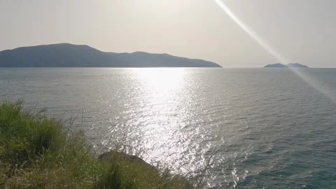 Tranquil panoramic coastal view with sunlit waves and distant islands across  Stock Footage 329911869