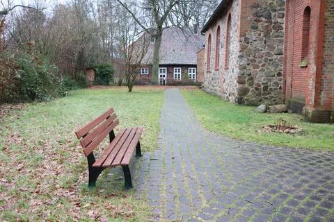 Tranquil park with bench, pathway, rustic building, greenery, serene atmosphere Stock Photos
