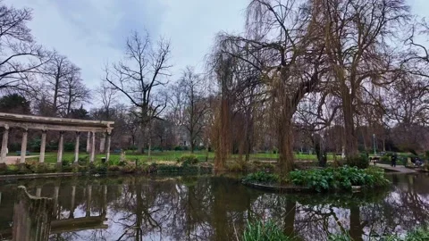 Tranquil pond and classical colonnade in Parc Monceau, Paris, France. Panning Stock Footage 304321434