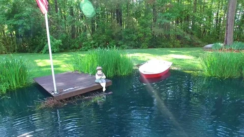 Tranquil Pond with dock and boat and american flag Stock-Footage 76944899