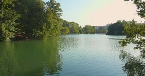 Tranquil pond surrounded by lush trees in Parc de la Tête d'Or, Lyon on a Stockbeeldmateriaal 284907529