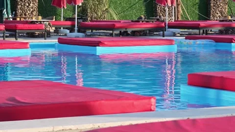 Tranquil poolside ambiance with vibrant red lounge chairs Stockbeeldmateriaal 312121956