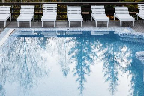 Tranquil Poolside with White Lounge Chairs and Reflective Water Stock Photos