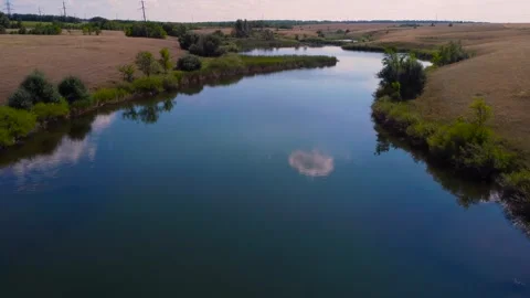 A tranquil river cutting through lush fields in a stunning landscape, drone Stock-Footage 283609753