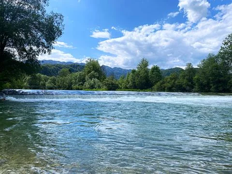 Tranquil River Flowing Through Lush Greenery Under Bright Blue Sky Stock Photos