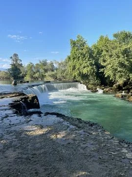 Tranquil River Flowing Through a Lush Green Forest on a Sunny Day Foto stock