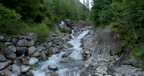 Tranquil river flowing through rocky terrain surrounded by lush greenery in Stockbeeldmateriaal 314076844