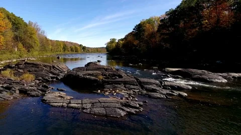 A tranquil river flows through a rocky autumn landscape Stock Footage 312679054