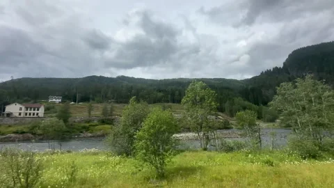 A tranquil river meanders through verdant hills under a cloudy sky Stock Footage 314076813